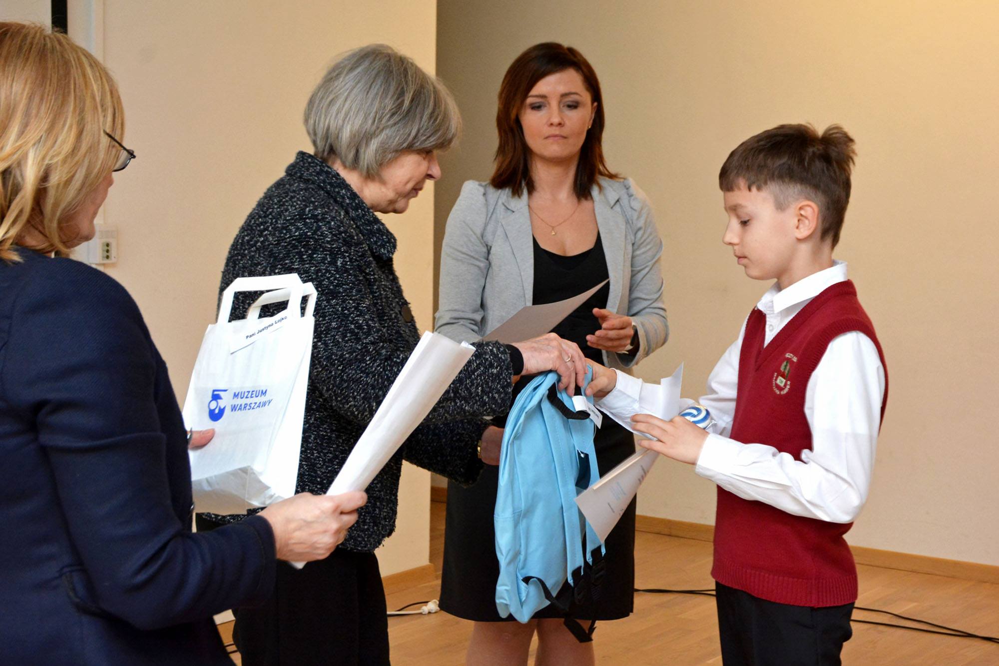 Dyrektor muzeum Ewa Nekanda Trepka wręcza nagrodę, niebieski plecak, laureatowi konkursu