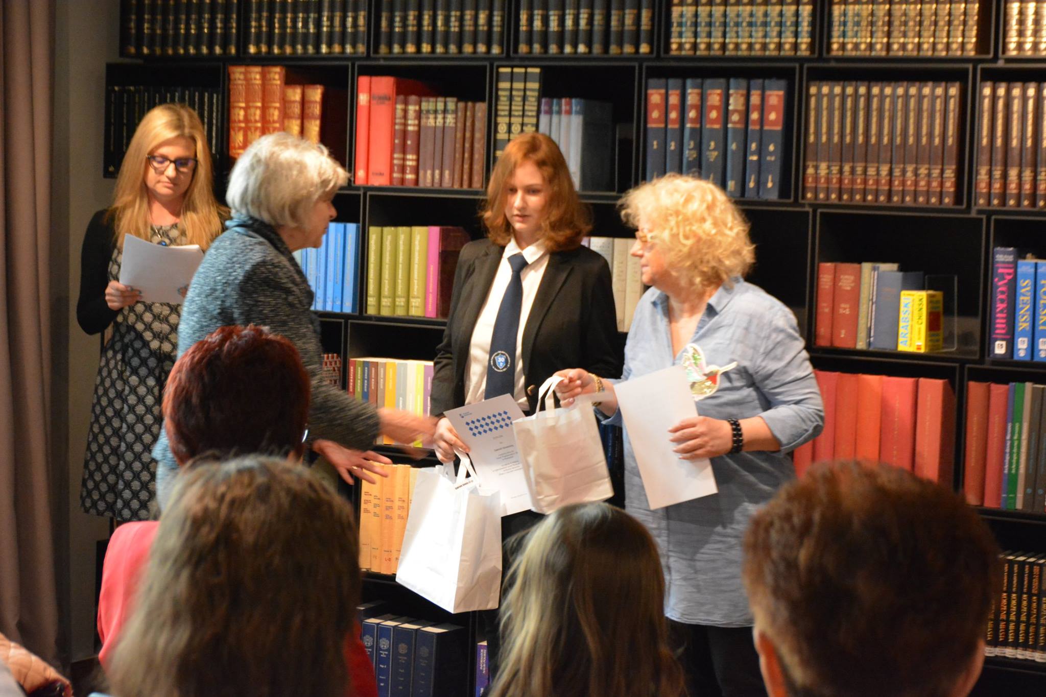 W bibliotece muzealnej dyrektor Ewa Nekanda Trepka wręcza nagrodę laureatce konkursu oraz jej opiekunowi.