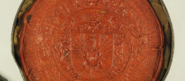 Czerwona, okrągła pieczęć z laki z odciśniętym orłem po środku i łacińskim napisem wokół.