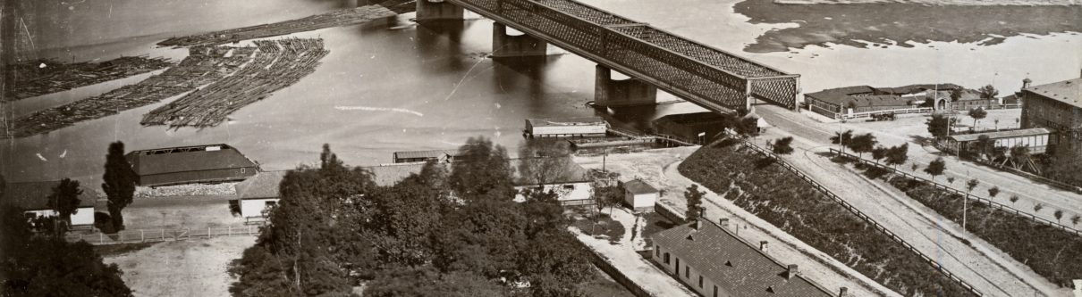 Czarno białe zdjęcie Warszawy z lotu ptaka. Widoczny fragment Wisły i nieistniejącego mostu Kierbedzia. mostu