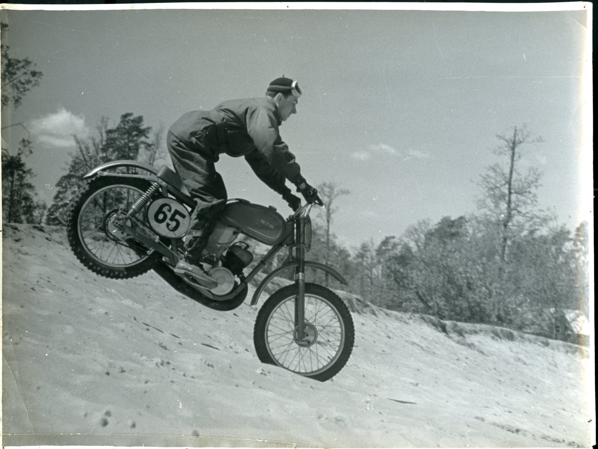 Czarno białe zdjęcie. Mężczyzna na motocyklu zjeżdżający z górki.