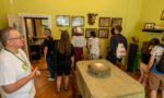 Zdjęcie. Grupa osób zwiedza pokój w willi Żabińskich. Na środku stół. Na ścianach obrazy, czaszka kozy.