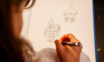 Zdjęcie. Kobieta szkicuje ołówkiem cerkiew.