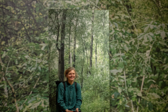 Zdjęcie. Katarzyna Wąsowska na tle fototapety gęstego zielonego lasu.